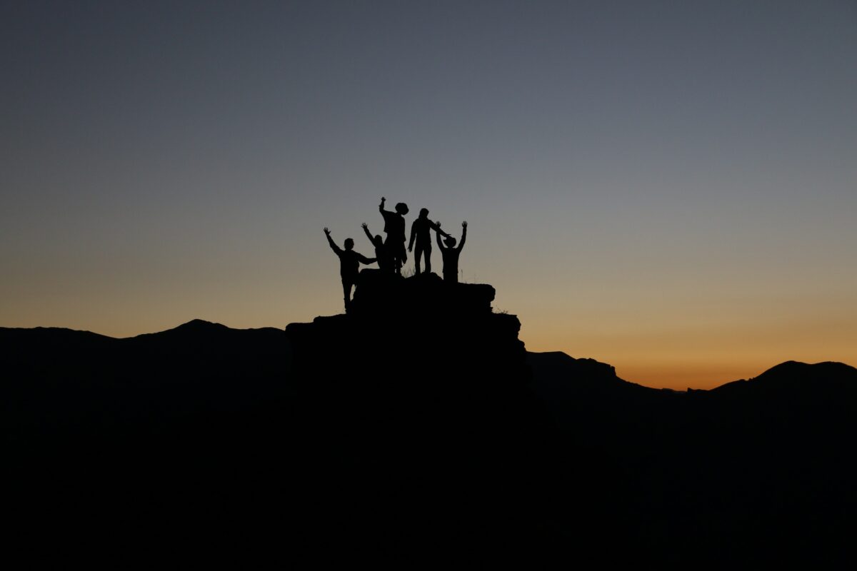 Photo of group standing on top of a cliff at dusk