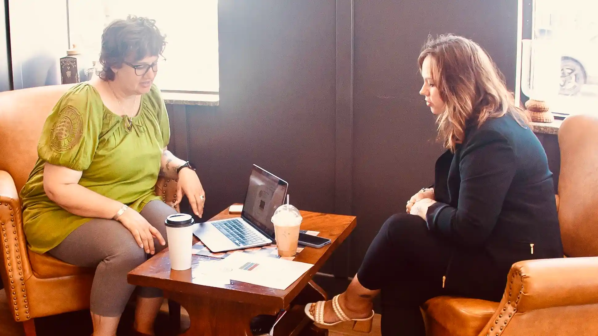 Two women sitting at a low table having a business meeting