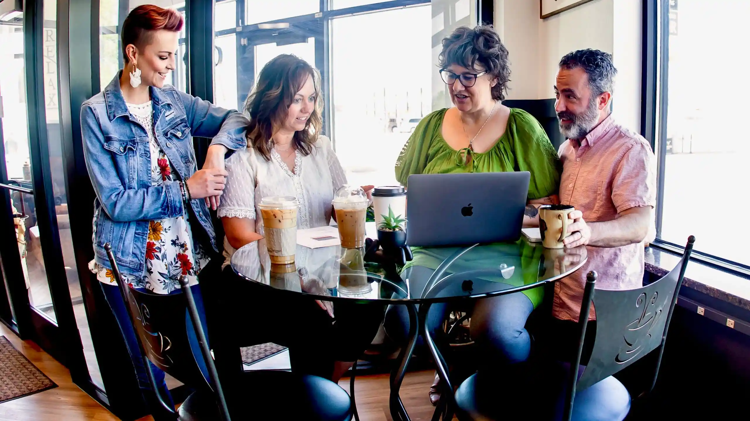 Group of professionals sitting or standing at a high top table looking at a laptop