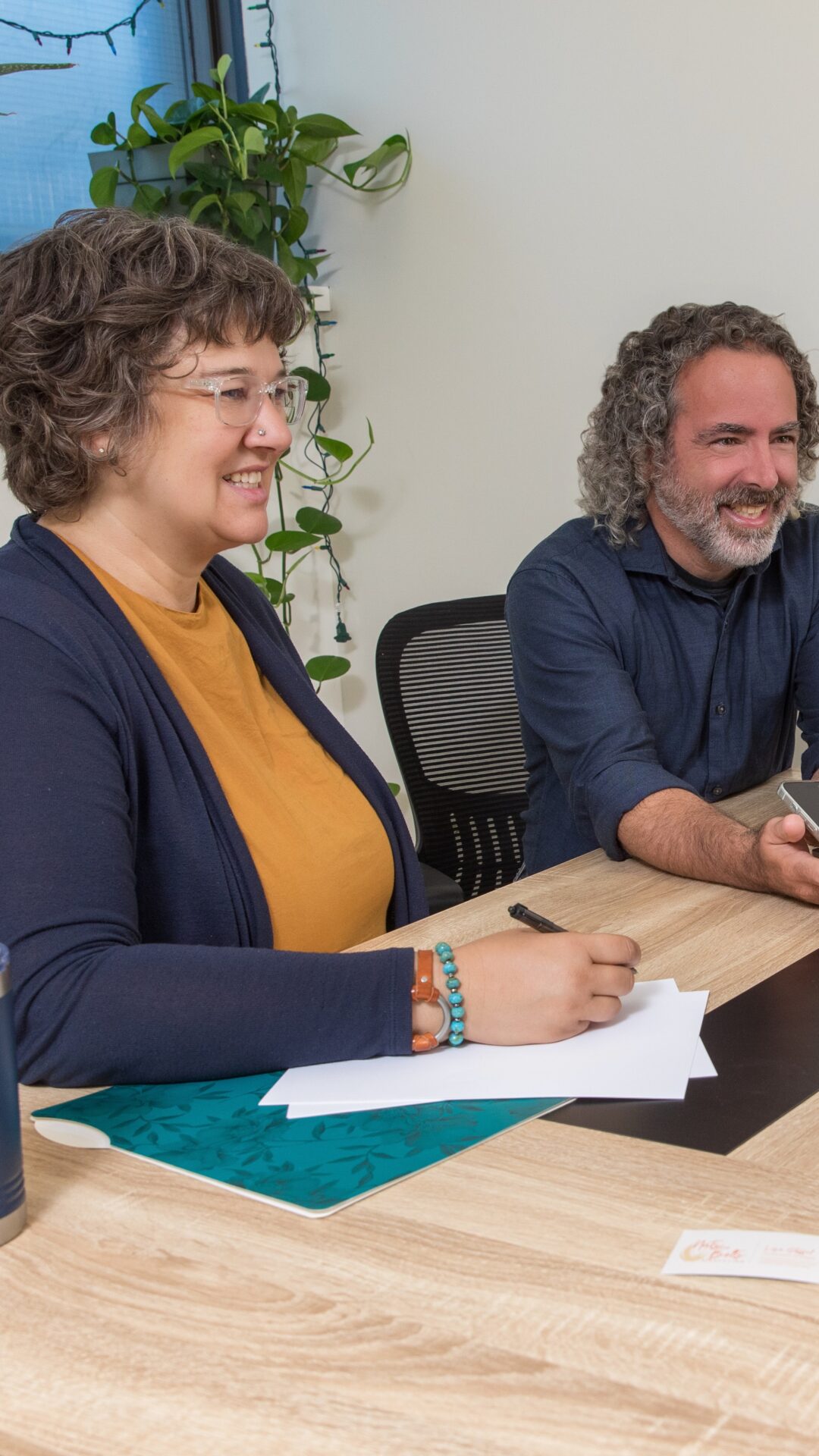 a woman and a man seated next to each other at a office table